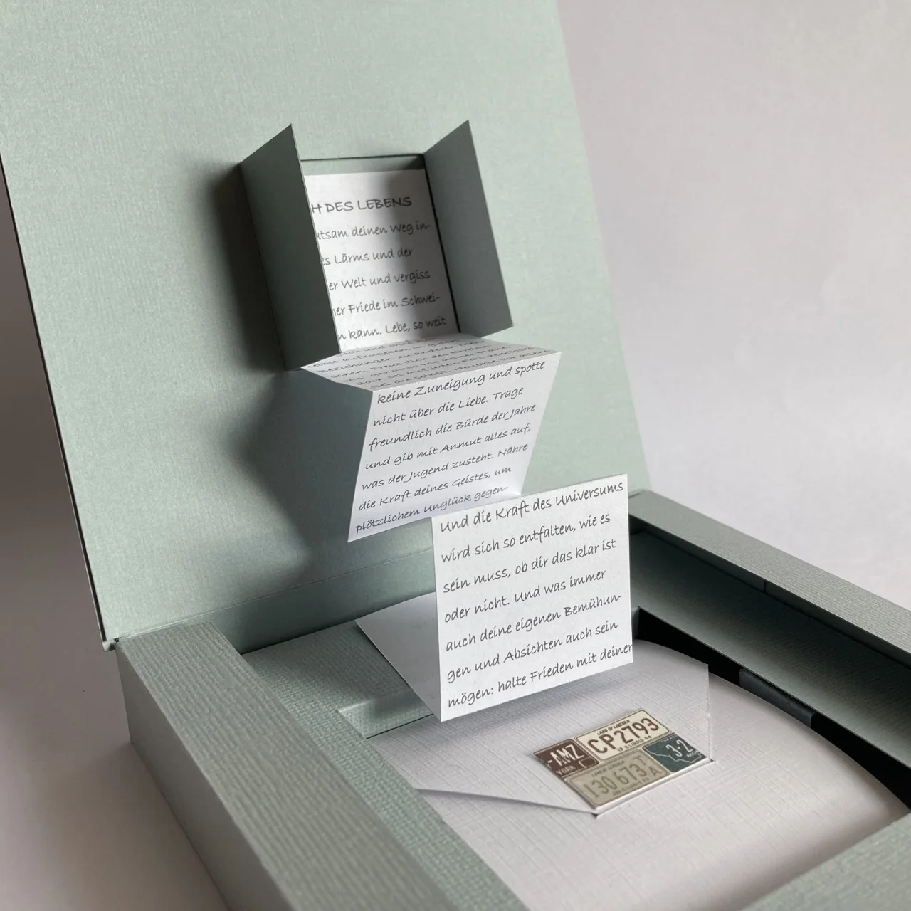 geöffnete quadratische Schachtel mit langem Spruch (Spruch des Lebens) und integriertem Fach mit Briefumschlag (Geldverpackung